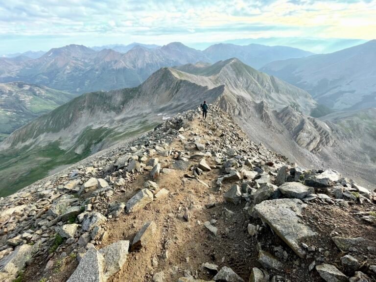 Person walking down from Mt Huron in Colorado, taking in the mountain landscape during a moment of reflection and integration